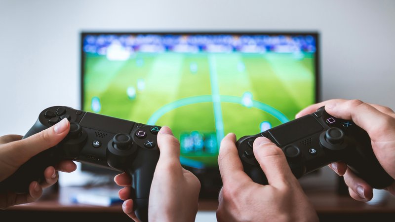 Spelcontrollers en een tv op de achtergrond, symbool voor het kiezen van een spelconsole