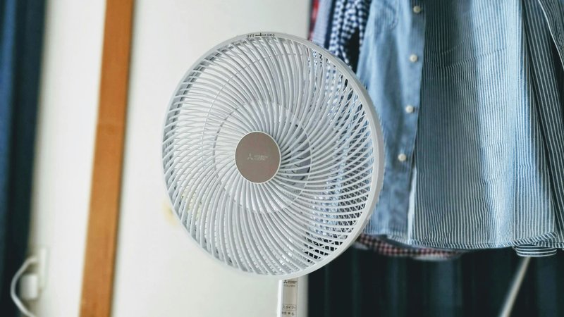 Close-up van een witte ventilator met rond ventilatorrooster in een kledingkast